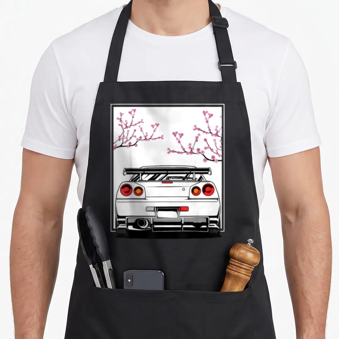 Cherry design imports vintage apron - Rear view white car with pink cherry blossom branches in line art style — shown on a black cotton canvas apron against a white background