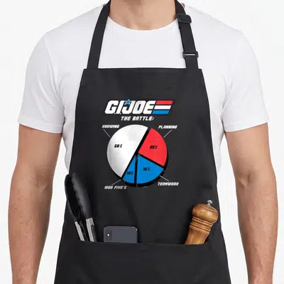 Joe pie apron - G.I. Joe pie chart showing knowing 50% planning 25% teamwork 15% high fives 10% — shown on a black cotton canvas apron against a white background
