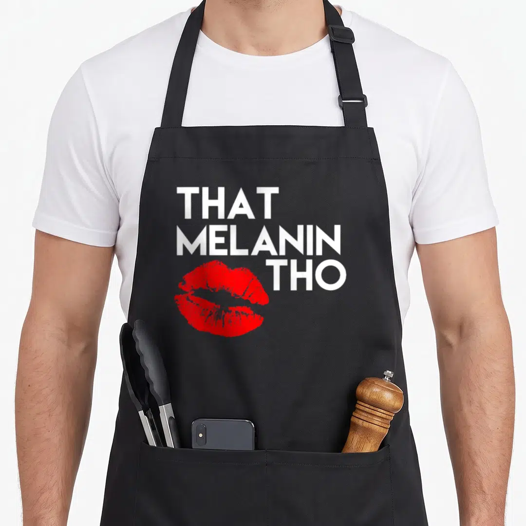 Tho business apron - White stacked text That Melanin Tho beside red lips graphic — shown on a black cotton canvas apron against a white background