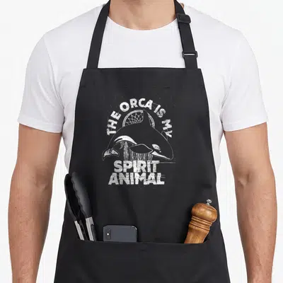Orca killer animal apron - Distressed orca and dreamcatcher graphic with spirit animal text — shown on a black cotton canvas apron against a white background