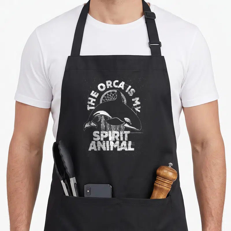 Orca killer animal apron - Distressed orca and dreamcatcher graphic with spirit animal text — shown on a black cotton canvas apron against a white background
