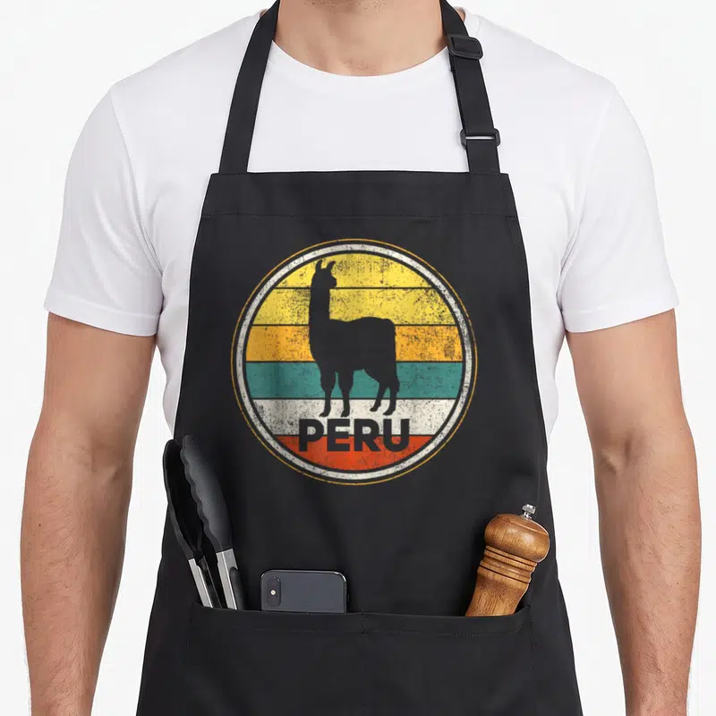 Vicuna peruvian apron - Grey llama silhouette over yellow orange teal white and red stripes with PERU text — shown on a black cotton canvas apron against a white background