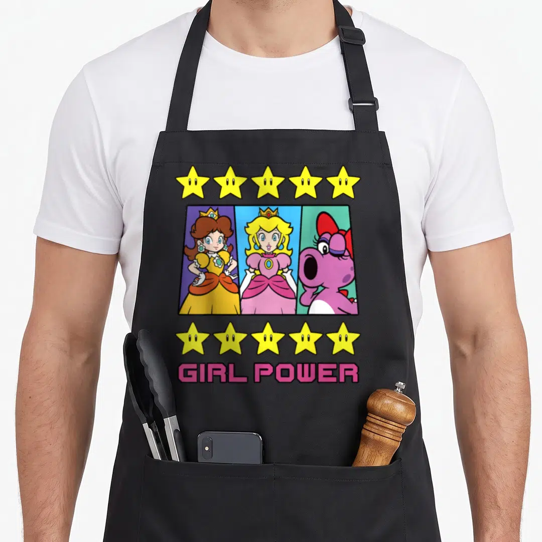 Birdo daisy apron - Three princesses in vertical panels with GIRL POWER text and yellow stars — shown on a black cotton canvas apron against a white background