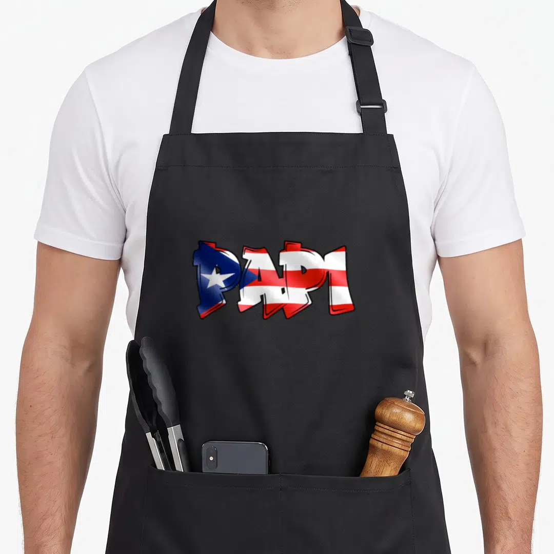 Papi pride apron - PAPI text filled with red white blue Puerto Rican flag pattern in bold graffiti style — shown on a black cotton canvas apron against a white background