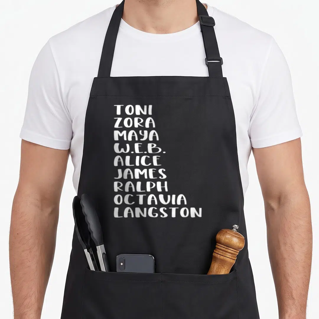 Famous african american aprons - Stacked white first names of Toni, Zora, Maya, W.E.B., Alice, James, Ralph, Octavia — shown on a black cotton canvas apron against a white background