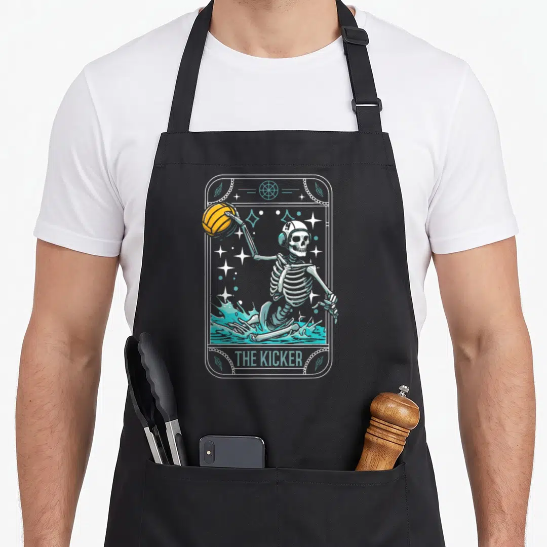 Water skeleton apron - Skeleton in teal water holding orange ball with THE KICKER text inside bordered frame — shown on a black cotton canvas apron against a white background