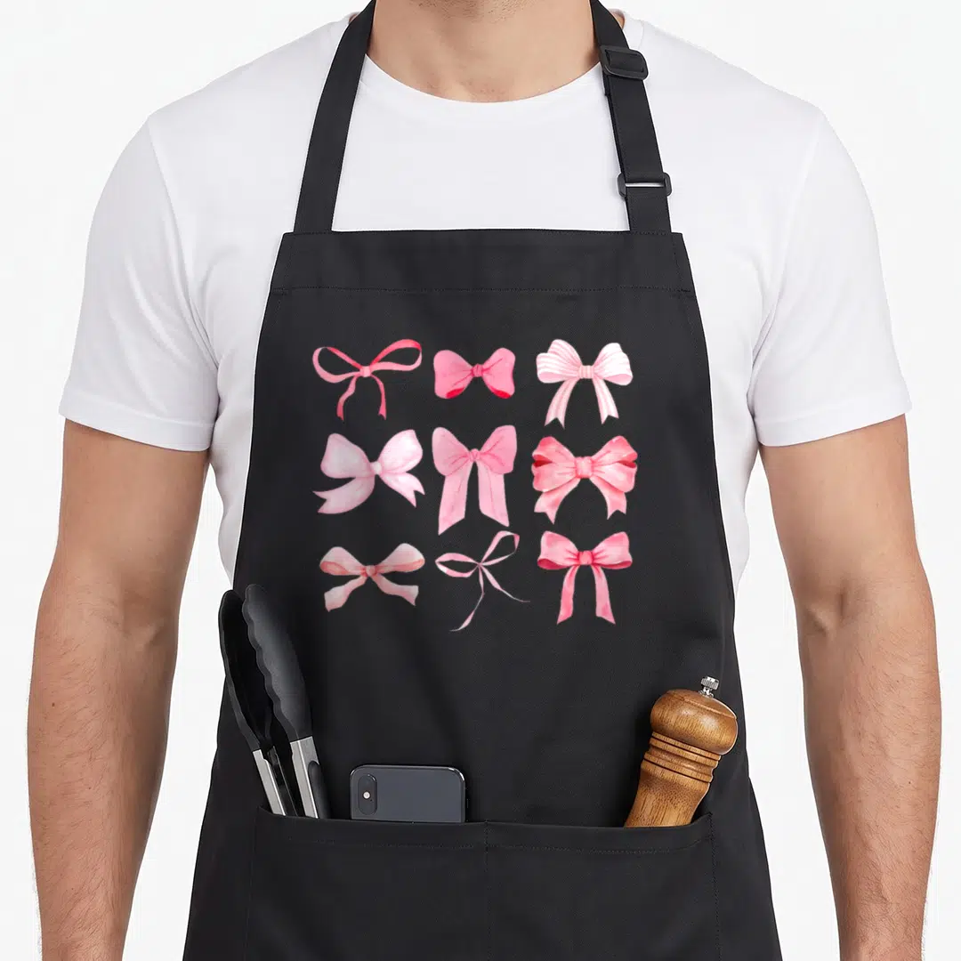 Bow ribbon apron - Nine realistic pink bows arranged in a 3x3 grid pattern — shown on a black cotton canvas apron against a white background
