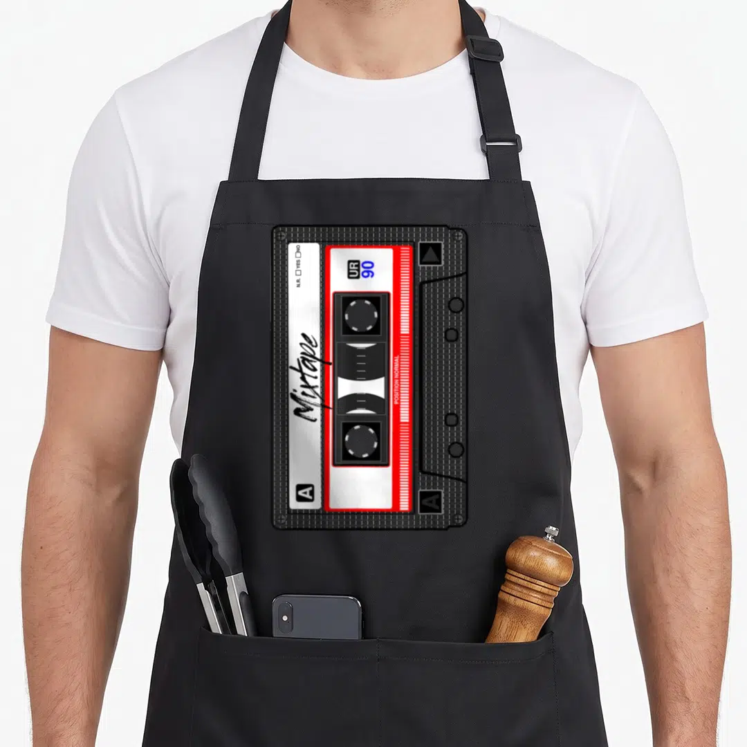 Cassette tape 80s apron - Black cassette tape with red border, white labels, Mixtape script, and UR 90 text — shown on a black cotton canvas apron against a white background