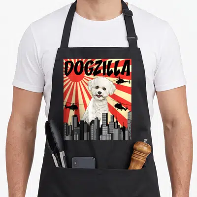 Japanese crazy dog lady apron - DOGZILLA text above white dog and helicopters against red sunburst — shown on a black cotton canvas apron against a white background
