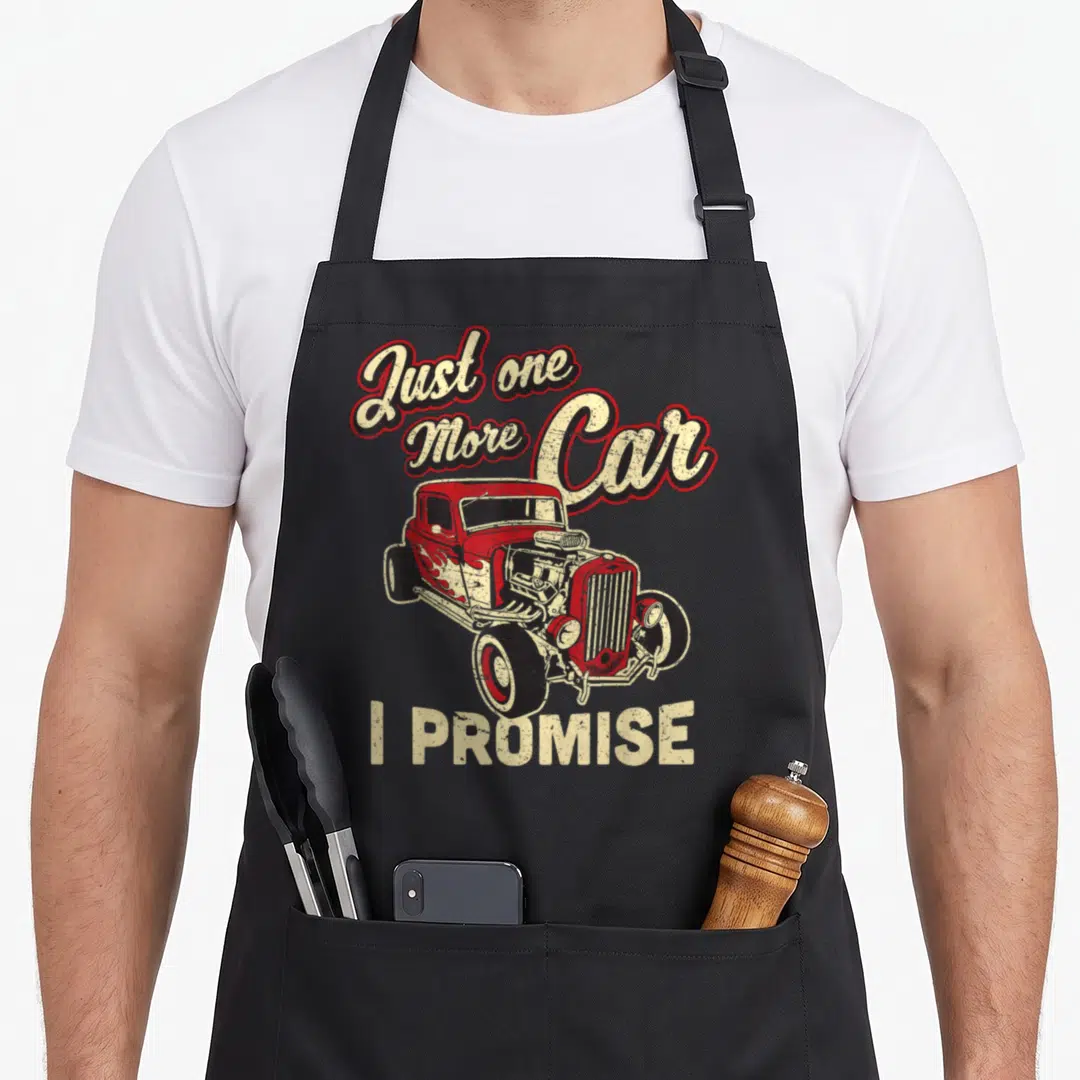 Fan promise car apron - Red hot rod illustration with arched text Just one More Car and straight text I PROMISE below — shown on a black cotton canvas apron against a white background