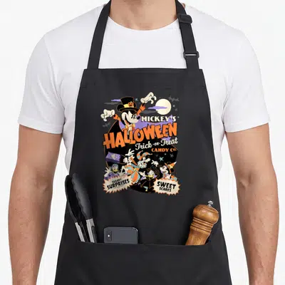 Halloween cotton candy apron - Mickey Mouse in top hat with orange Halloween text and costumed friends under a moon — shown on a black cotton canvas apron against a white background