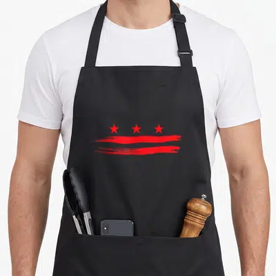 Flag capitol hill apron - Three red stars above two horizontal red brush strokes on black fabric — shown on a black cotton canvas apron against a white background