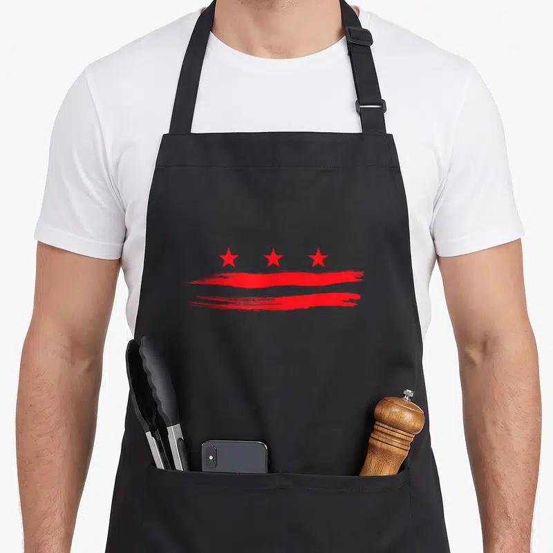 Flag capitol hill apron - Three red stars above two horizontal red brush strokes on black fabric — shown on a black cotton canvas apron against a white background