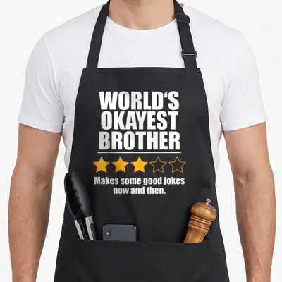 Okayest birthday brother apron - WORLD'S OKAYEST BROTHER text with three filled and two outlined orange stars below — shown on a black cotton canvas apron against a white background