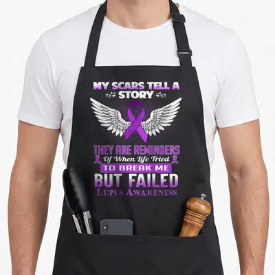 Scar story of the apron - Purple awareness ribbon with white wings and stacked text reading My Scars Tell A Story — shown on a black cotton canvas apron against a white background