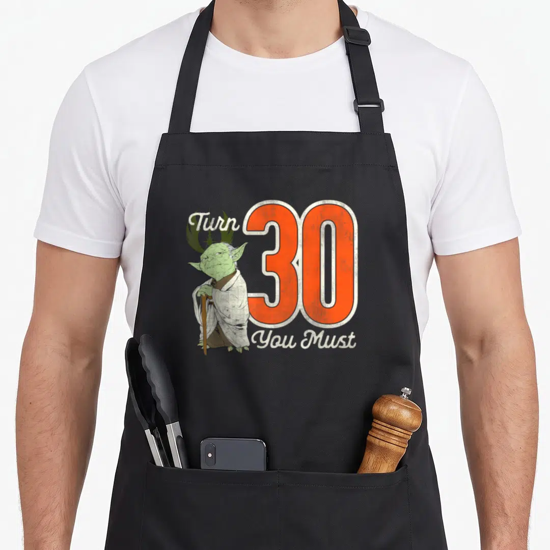 Yoda 30th birthday apron - Cartoon Yoda standing beside a large orange number 30 with white script text — shown on a black cotton canvas apron against a white background