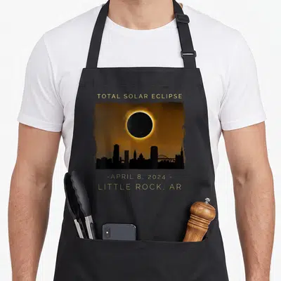 Total arkansas girl apron - Gold text Total Solar Eclipse over orange sky and black Little Rock skyline — shown on a black cotton canvas apron against a white background