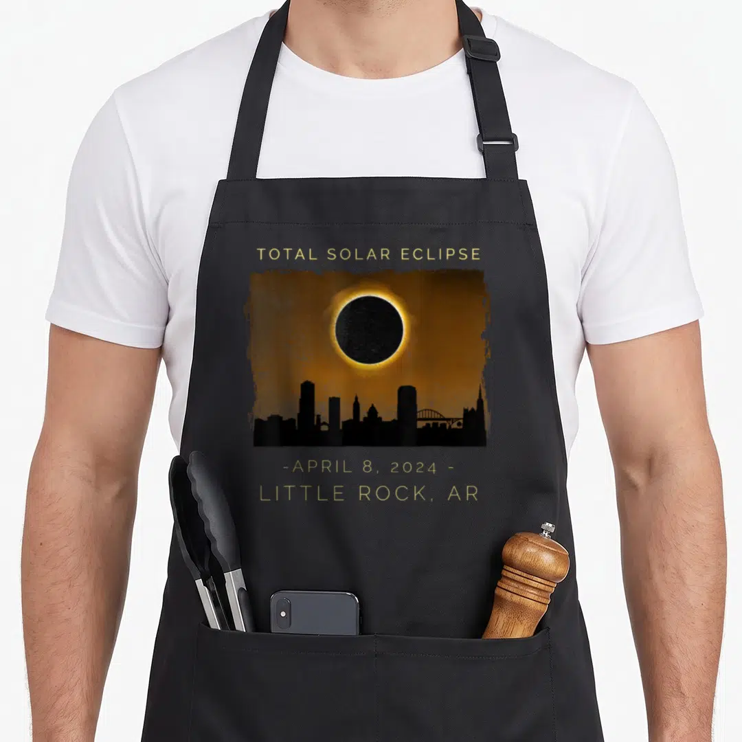 Total arkansas girl apron - Gold text Total Solar Eclipse over orange sky and black Little Rock skyline — shown on a black cotton canvas apron against a white background