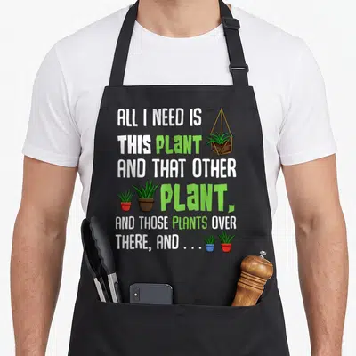 Funny plant apron - Stacked text ALL I NEED IS THIS PLANT with potted succulents in red blue and brown pots — shown on a black cotton canvas apron against a white background