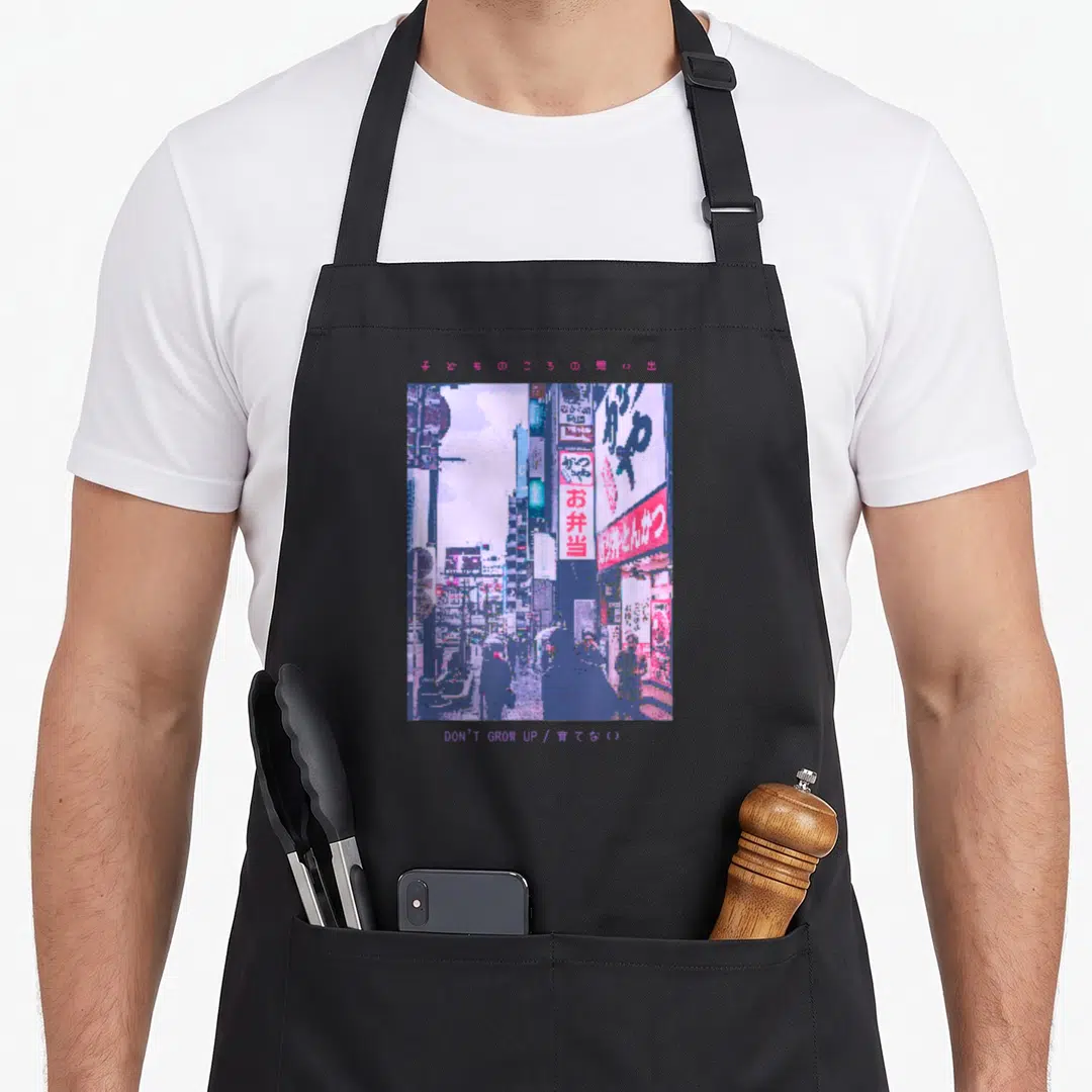 Tokyo streetwear apron - Pixelated city street scene in purple and pink with Japanese text and English phrase — shown on a black cotton canvas apron against a white background