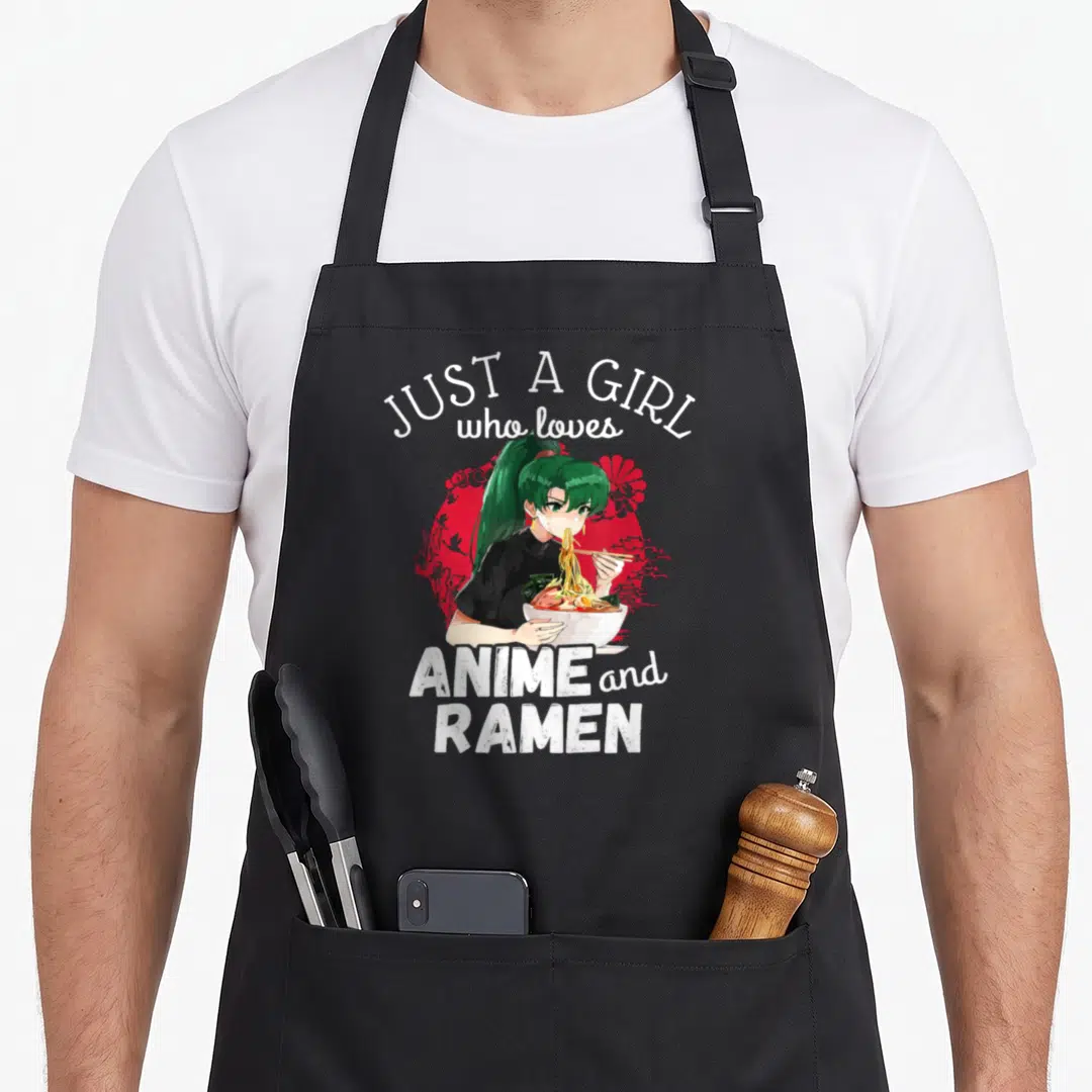 Ramen kawaii anime apron - Just A Girl who loves Anime and Ramen text with green haired anime girl eating noodles — shown on a black cotton canvas apron against a white background