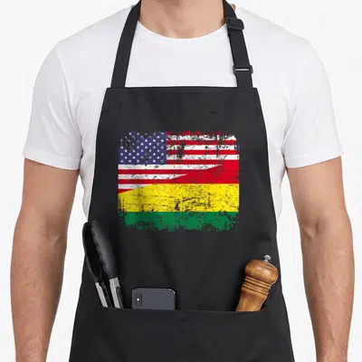 Bolivian root american flag apron - Distressed split flag design with blue stars red stripes and yellow green bands — shown on a black cotton canvas apron against a white background