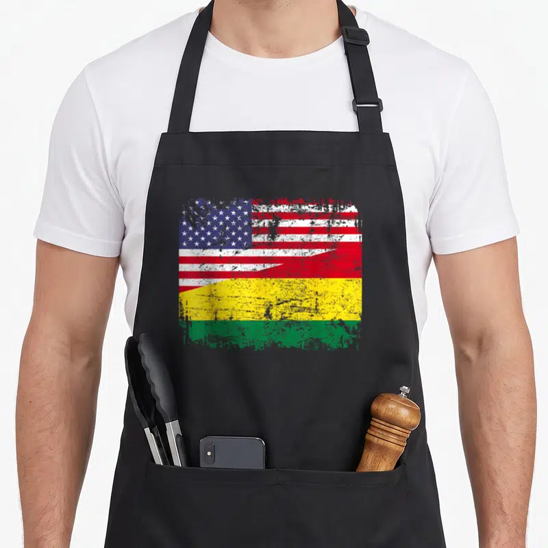 Bolivian root american flag apron - Distressed split flag design with blue stars red stripes and yellow green bands — shown on a black cotton canvas apron against a white background