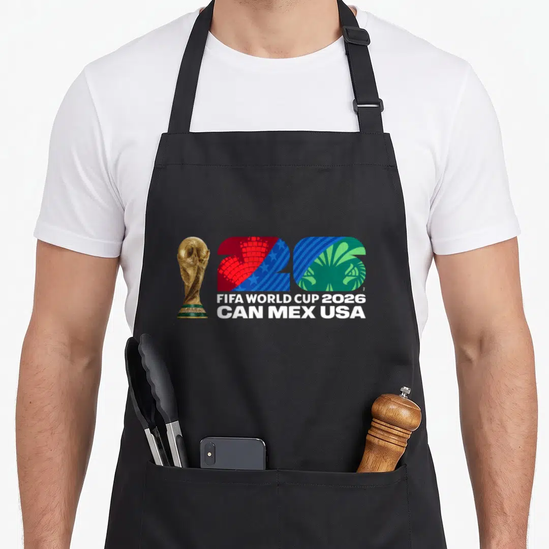 Cup26 country apron - Gold FIFA trophy beside red blue and green 26 with stacked FIFA WORLD CUP 2026 CAN MEX USA text — shown on a black cotton canvas apron against a white background