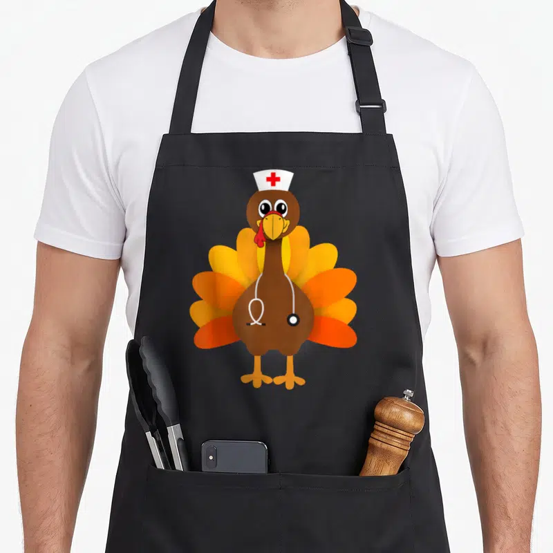 Thanksgiving turkey apron - Cartoon brown turkey wearing white nurse hat with red cross and stethoscope — shown on a black cotton canvas apron against a white background