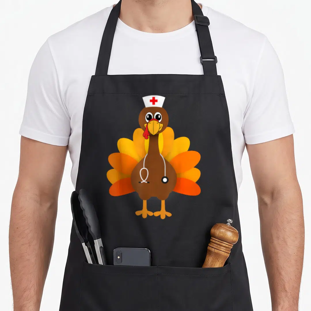 Thanksgiving turkey apron - Cartoon brown turkey wearing white nurse hat with red cross and stethoscope — shown on a black cotton canvas apron against a white background