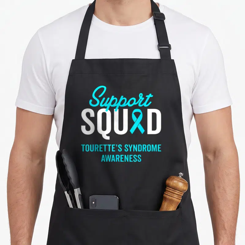 Warrior tourette awareness apron - Support Squad text with cyan ribbon replacing A and Tourette's Syndrome Awareness — shown on a black cotton canvas apron against a white background