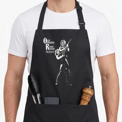 Tribute ozzy osbourne apron - Ozzy SBOURNE Randy BOADS TRIBUTE text with guitarist illustration in white and grey — shown on a black cotton canvas apron against a white background