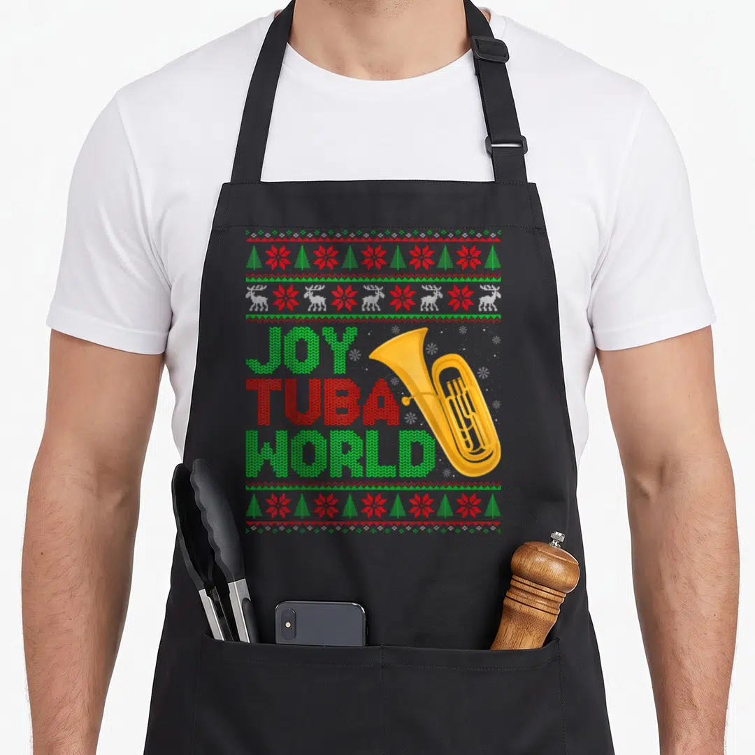 Tuba ugly christmas apron - Stacked Joy Tuba World text with gold tuba and reindeer borders in red green gold — shown on a black cotton canvas apron against a white background