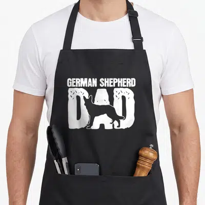 Father dog mom apron - White distressed text GERMAN SHEPHERD DAD with dog silhouette overlay — shown on a black cotton canvas apron against a white background