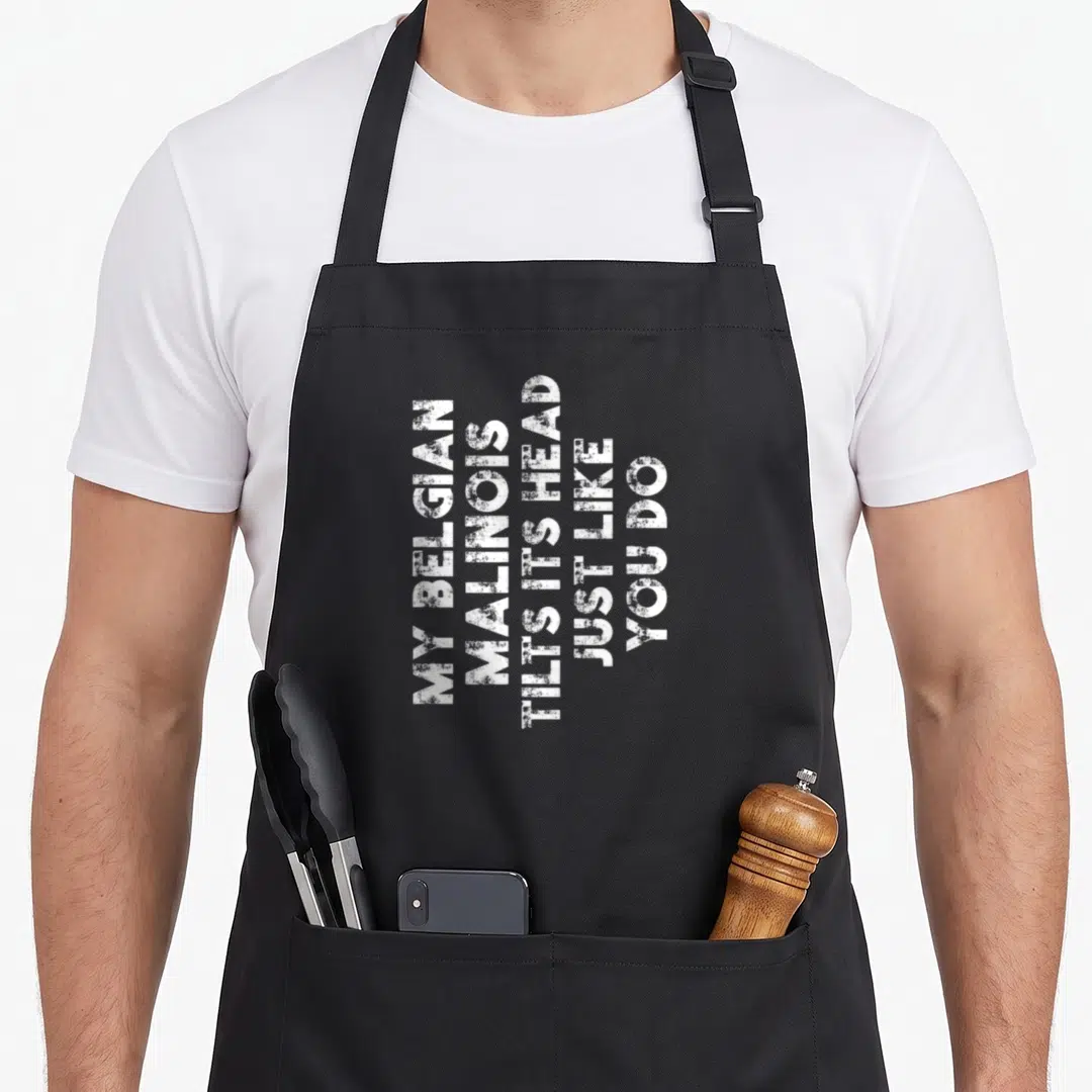 Funny belgian dog apron - White stacked text reading My Belgian Malinois Tilts Its Head Just Like You Do — shown on a black cotton canvas apron against a white background