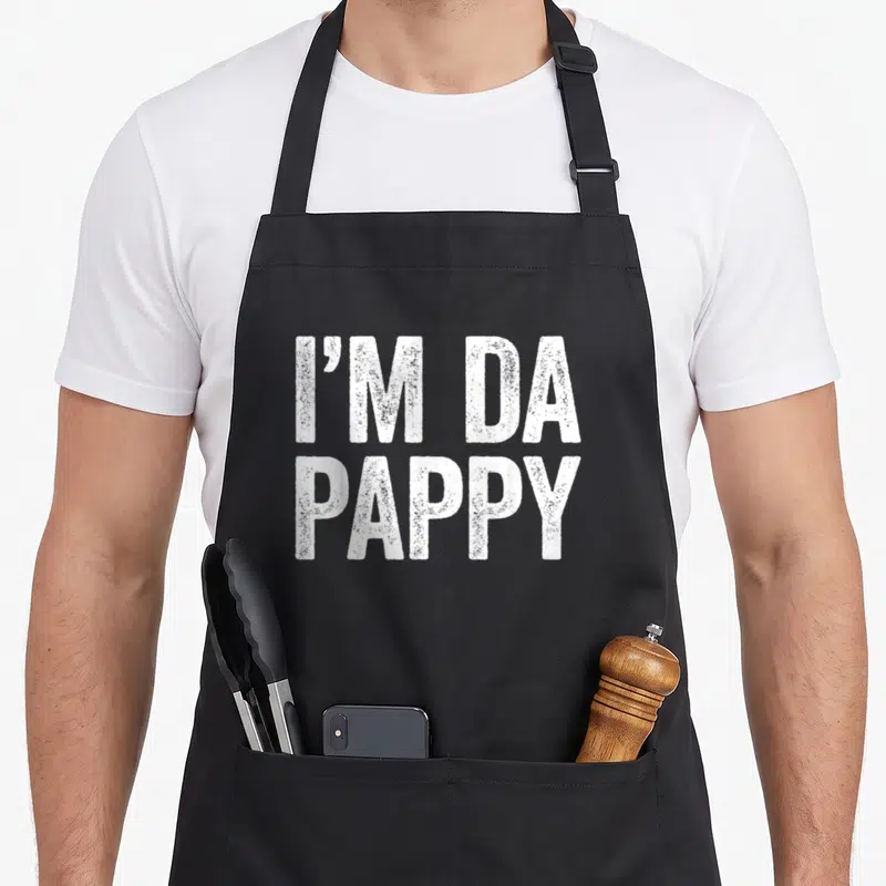 Vintage pappy father day apron - White distressed text reading I'M DA PAPPY stacked in two lines — shown on a black cotton canvas apron against a white background