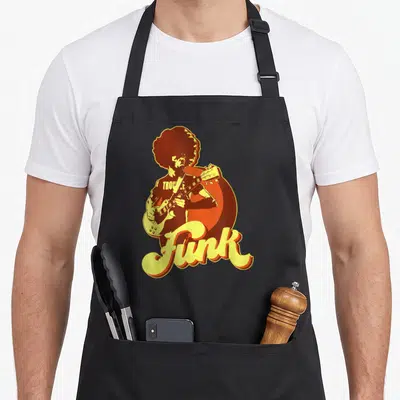 Guitarist 70s apron - Retro musician silhouette playing guitar with Trouble and Funk text in orange and yellow — shown on a black cotton canvas apron against a white background