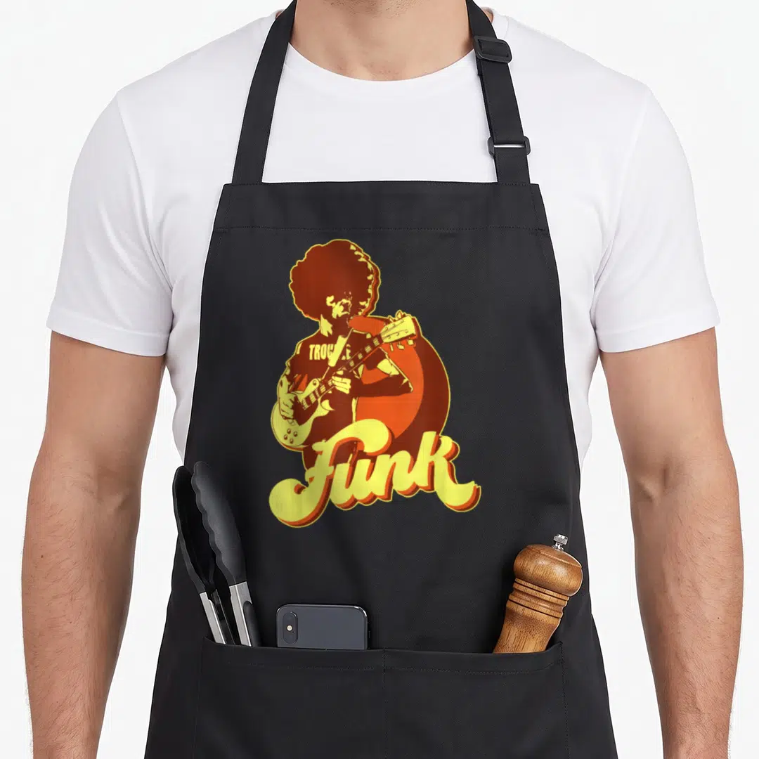 Guitarist 70s apron - Retro musician silhouette playing guitar with Trouble and Funk text in orange and yellow — shown on a black cotton canvas apron against a white background