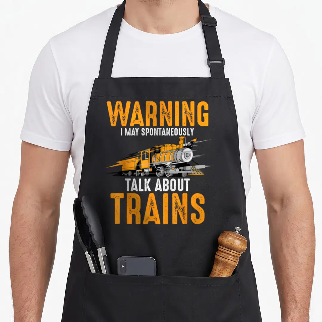 Warning talk apron - Orange cartoon steam train with lightning bolt and stacked warning text — shown on a black cotton canvas apron against a white background