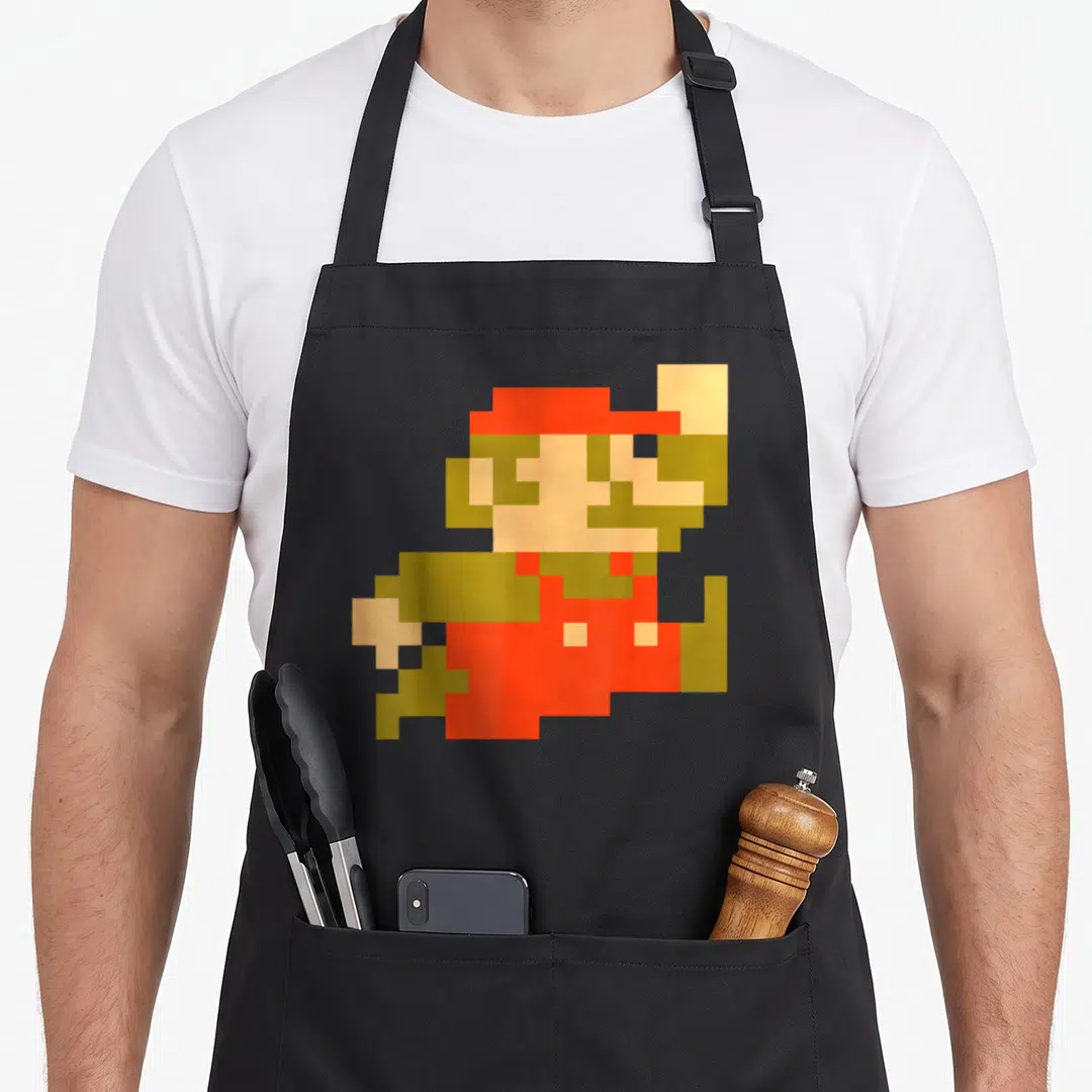 Jump boy pixel apron - Pixel art character in red brown peach on black bib apron — shown on a black cotton canvas apron against a white background