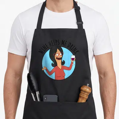 Linda bobs burger apron - Cartoon woman in red shirt and glasses holding wine glass inside light blue circle — shown on a black cotton canvas apron against a white background