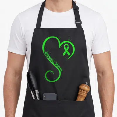 Lymphoma lime green apron - Green heart outline containing awareness ribbon and scattered dots — shown on a black cotton canvas apron against a white background
