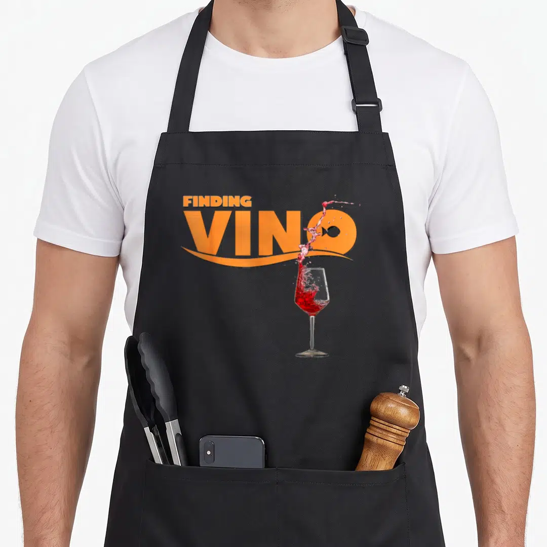 Finding wine apron - Orange FINDING VINO text with red wine splash and fish icon inside the O — shown on a black cotton canvas apron against a white background