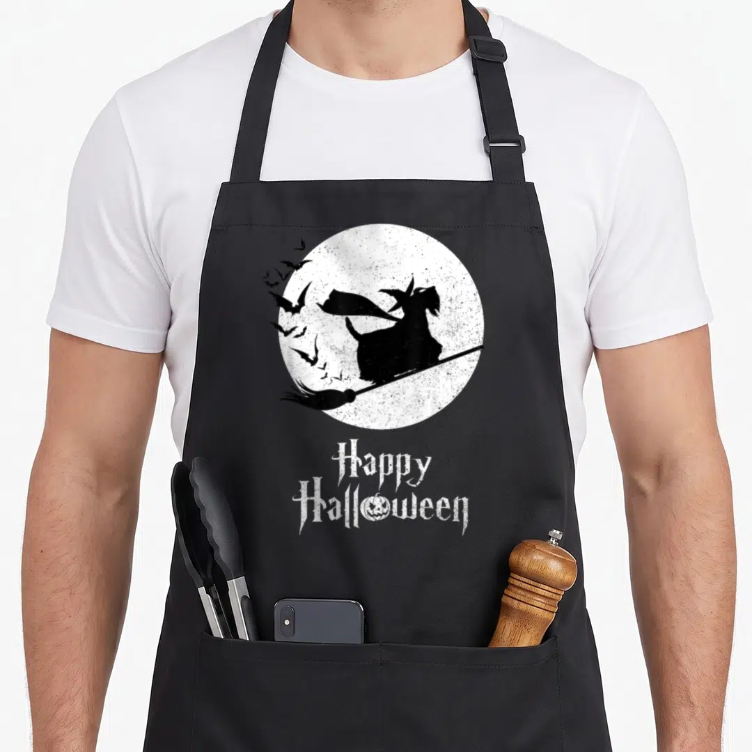 Scottie halloween witch apron - Black dog silhouette on broom in front of white moon with Happy Halloween text — shown on a black cotton canvas apron against a white background