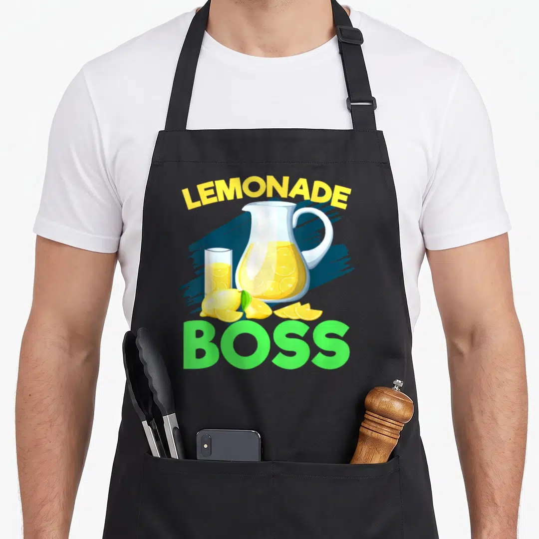Crew boss lemonade apron - Lemonade Boss text over pitcher glass and yellow lemons on blue brushstroke — shown on a black cotton canvas apron against a white background