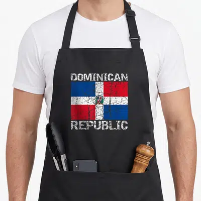 Dominican distressed apron - Distressed Dominican Republic flag print with DOMINICAN REPUBLIC text in red white blue — shown on a black cotton canvas apron against a white background