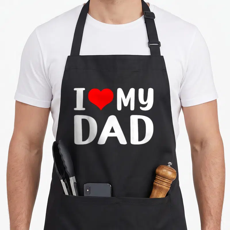 Daddy grandad aprons - Red heart between white words I MY and DAD below — shown on a black cotton canvas apron against a white background