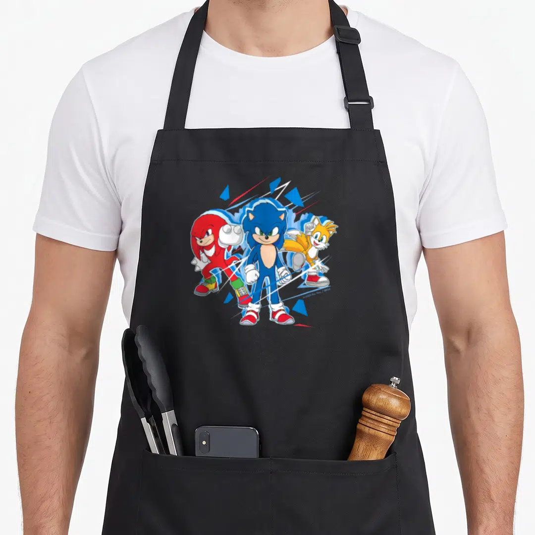 Funny crazy hedgehog man apron - Sonic, Tails, and Knuckles standing side-by-side with blue and red shards and bottom — shown on a black cotton canvas apron against a white background