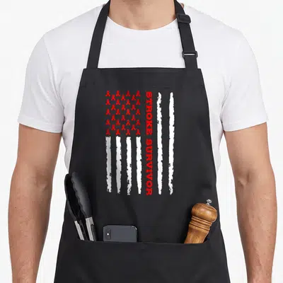 Stroke awareness ribbon apron - Red ribbons and white distressed stripes forming a flag with vertical STROKE SURVIVOR — shown on a black cotton canvas apron against a white background