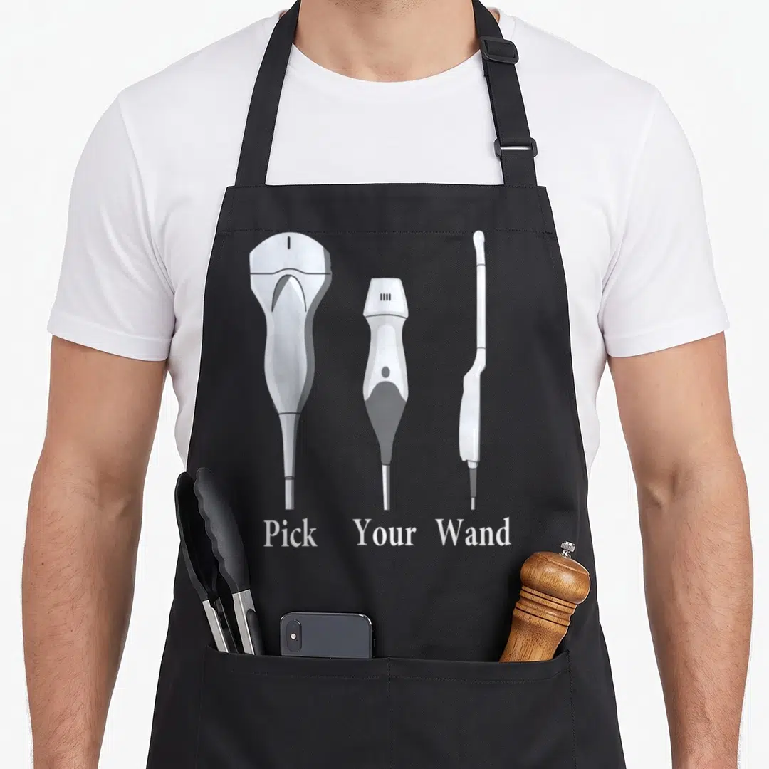 Ultrasound future sonographer apron - Three white and grey ultrasound wands arranged above Pick Your Wand text — shown on a black cotton canvas apron against a white background